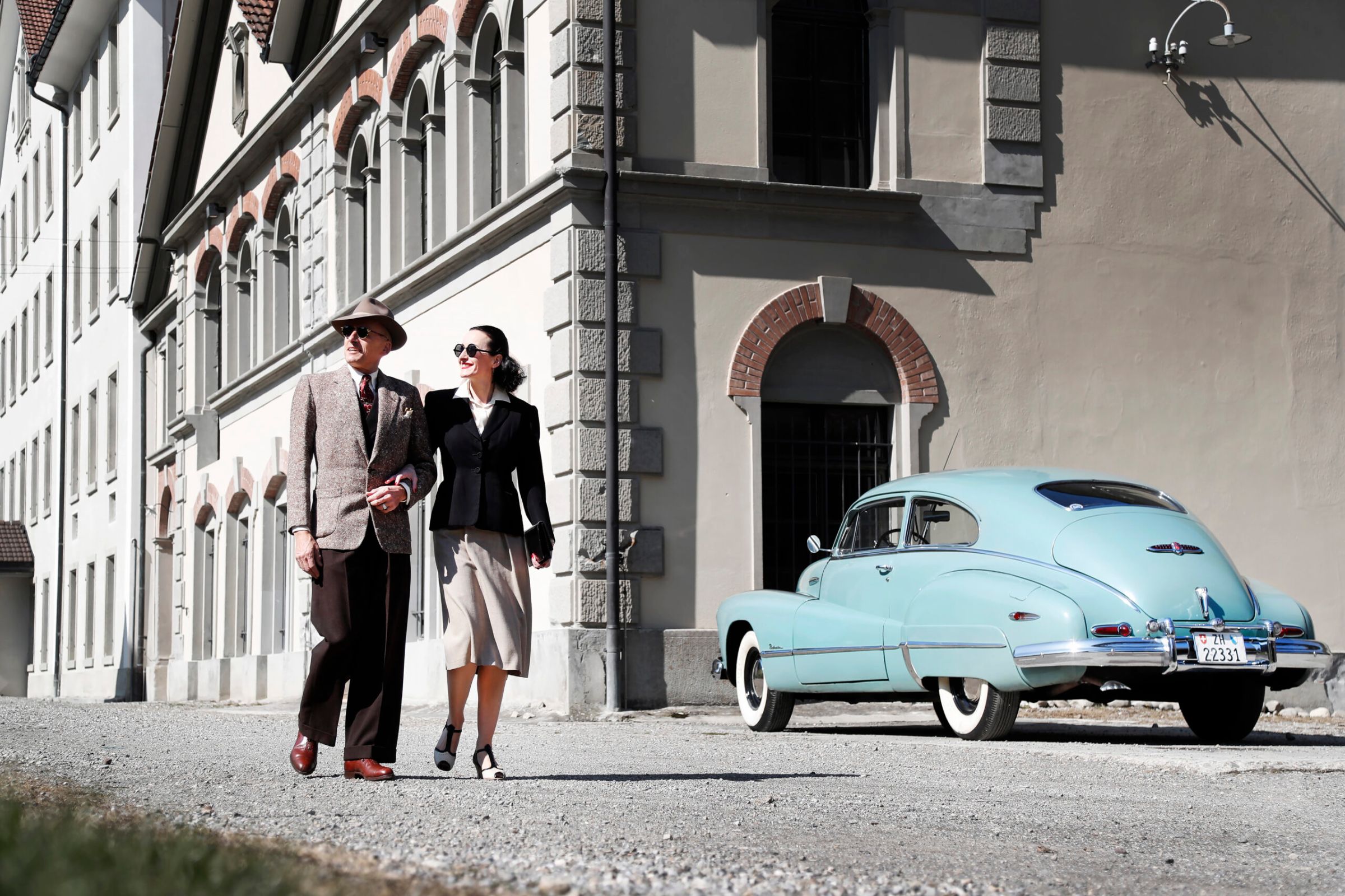 Paar vor historischem Gebäude, daneben der Buick