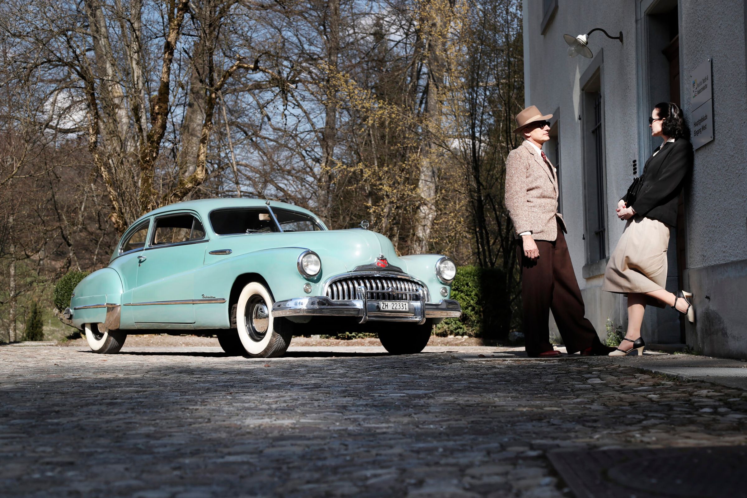 Paar in Vintage-Kleidung neben einem hellblauen Buick